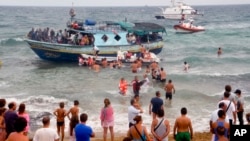 Vacationers joined Italian Coast Guard officers to help migrants from Eritrea ashore two years ago in August near the seaport of Siracusa after a long and treacherous journey.