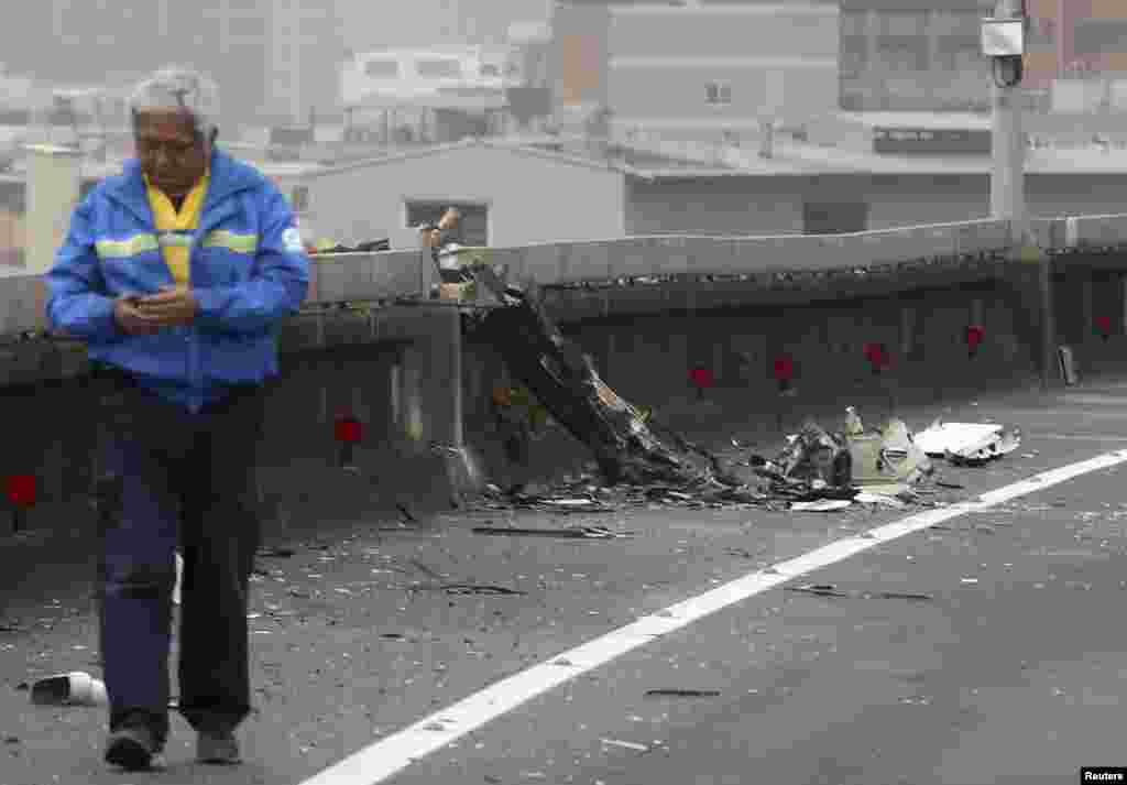 A man walks past next to the wreckage of a TransAsia Airways plane which hit a motorway before crash landing in a river, in New Taipei City.