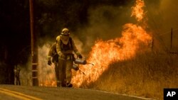 Firefighters light a backfire while trying to keep a wildfire from jumping Santa Ana Road near Ventura, California, Dec. 9, 2017. 