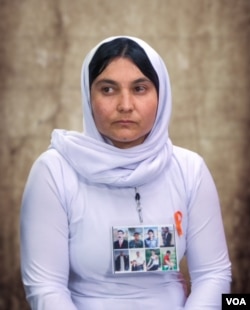 Shireen Jardo talks about her enslavement by the Islamic State during an interview with Voice of America. She wears a poster with pictures of her three brothers and five other members of her extended family still missing in IS territory.