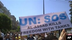 In this citizen journalism image made on a mobile phone and acquired by the AP, taken on Friday, May 6, 2011, Syrian anti-government protesters carry a banner during a rally in the central city of Homs, Syria