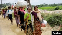 FILE - Rohingya refugees, who crossed the border from Myanmar two days earlier, walk after they received permission from the Bangladesh army to continue their way to Kutupalong refugee camp, near Cox's Bazar, Bangladesh, Oct. 19, 2017.