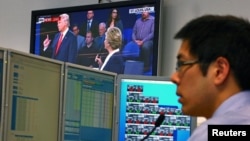 Seorang pialang di meja kerjanya di kantor Citibank di Sydney, Australia, sementara televisi menayangkan debat antara Hillary Clinton dan Donald Trump (10/10). 
