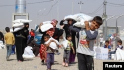 People who fled the Islamic State's strongholds of Hawija and Mosul receive aid at a camp for displaced people in Daquq, Iraq, Oct. 13, 2016.