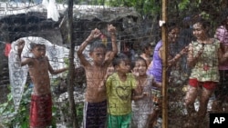 Filipino children watch as arrested drug suspects, not shown, wait outside an alleged drug den following a raid where two suspects were killed and about 90 people arrested during operations as part of the continuing "War on Drugs" campaign of Philippine P