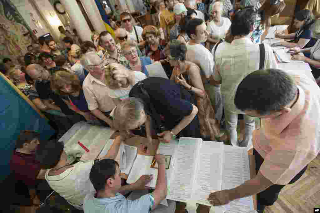 Ukrainians stand in line to receive their ballots at a polling station during elections in Kyiv, May 25, 2014.