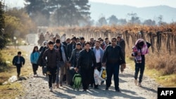 FILE - Migrants and refugees are seen walking after crossing the Greek-Macedonian border near Gevgelija, Nov. 16, 2015. 