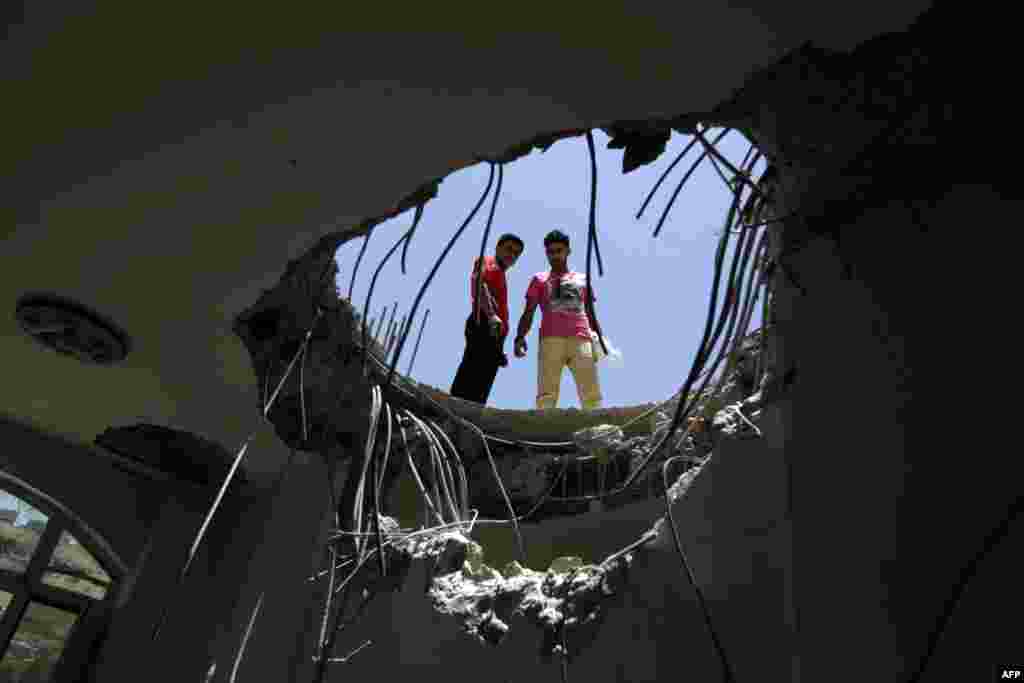 Yemenis look down through a hole in the roof of a house which was damaged the day before during an air strike by Saudi-led coalition warplanes on the nearby base on Fajj Attan hill in the capital Sanaa. 