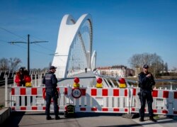 FILE - German police officers guard a closed bridge at the French-German border at the river Rhine in Kehl, Germany, March 16, 2020. German government allowed only restricted access from France to Germany.