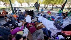 FILE - Migrants rest on a gazebo at a park after they were expelled from the U.S. and pushed by Mexican authorities off an area where they had been staying, in Reynosa, Mexico, March 20, 2021.