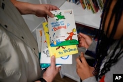 Tim McNeeley, left, helps students pick books to read during an after-school literacy program in Atlanta on Thursday, April 6, 2023. (AP Photo/Alex Slitz)