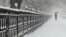 A woman walks along a park fence during a snowfall in Almaty, Kazakhstan