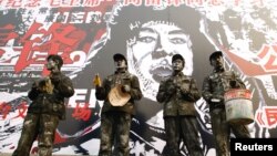中国演员身着工作人员服装在“人民英雄”雷锋画像前演出