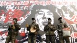 Chinese actors dressed as workers perform in front of a portrait of "People's Hero" Lei Feng to urge people to learn from the model soldier during a performance in Beijing March 1, 2003. 