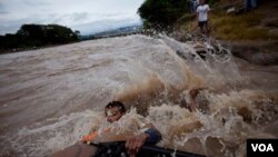 El salvadoreño Edwin Enríquez intenta cruzar junto con su familia a territorio seguro luego de que el puente internacional que divide El Salvador con Guatemala colapsara por las lluvias.