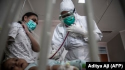 Seorang dokter merawat bayi yang dites positif virus corona Covid-19 di sebuah rumah sakit di Bogor pada 23 Juni 2021, ketika tingkat infeksi di Indonesia melonjak dan rumah sakit kebanjiran pasien baru. (Foto: AFP/Aditya Aji)