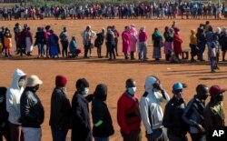 FILE - People affected by the coronavirus economic downturn line up to receive food aid in Pretoria, South Africa, May 20, 2020.