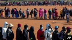 FILE - People affected by the coronavirus economic downturn line up to receive food aid in Pretoria, South Africa, May 20, 2020.