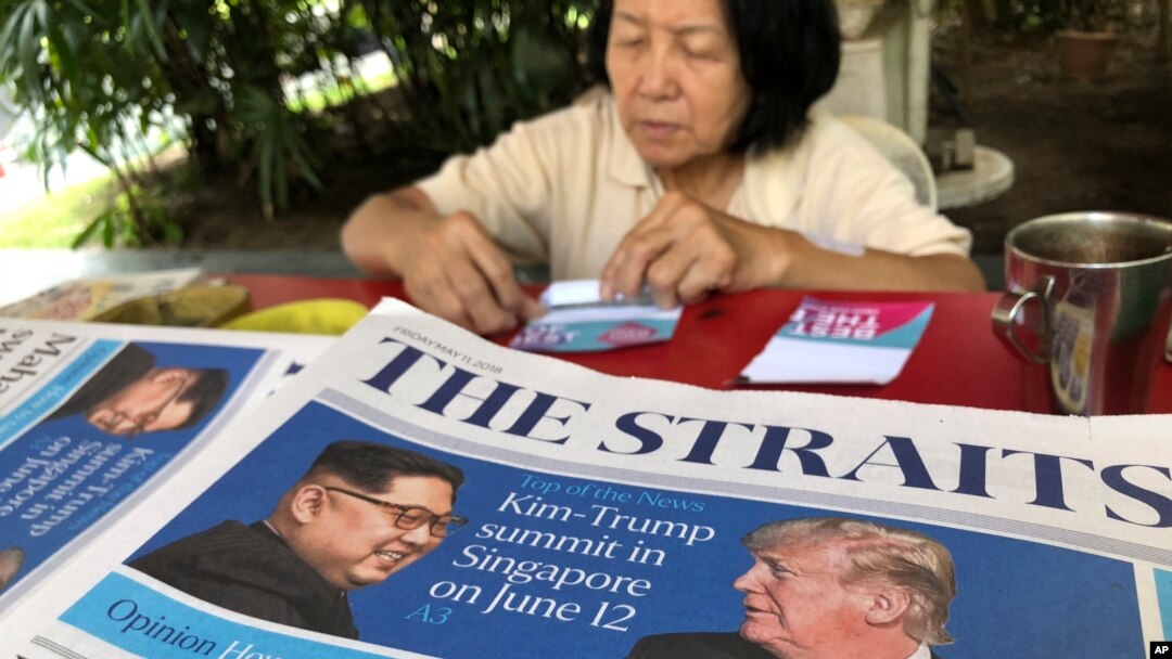 Seorang penjual koran di Singapura, tengah menghitung uangnya di dekat koran yang menampilkan foto Presiden AS Donald Trump (kanan) dan Pemimpin Korut Kim Jong-un pada halaman depannya, 11 Mei 2018. (Foto: dok).