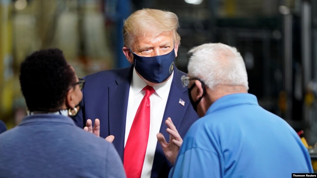 El presidente Donald Trump conversa con dos trabajadores en una planta de producción de la compañía Whirlpool en Clyde, Ohio, el jueves 6 de agosto de 2020.