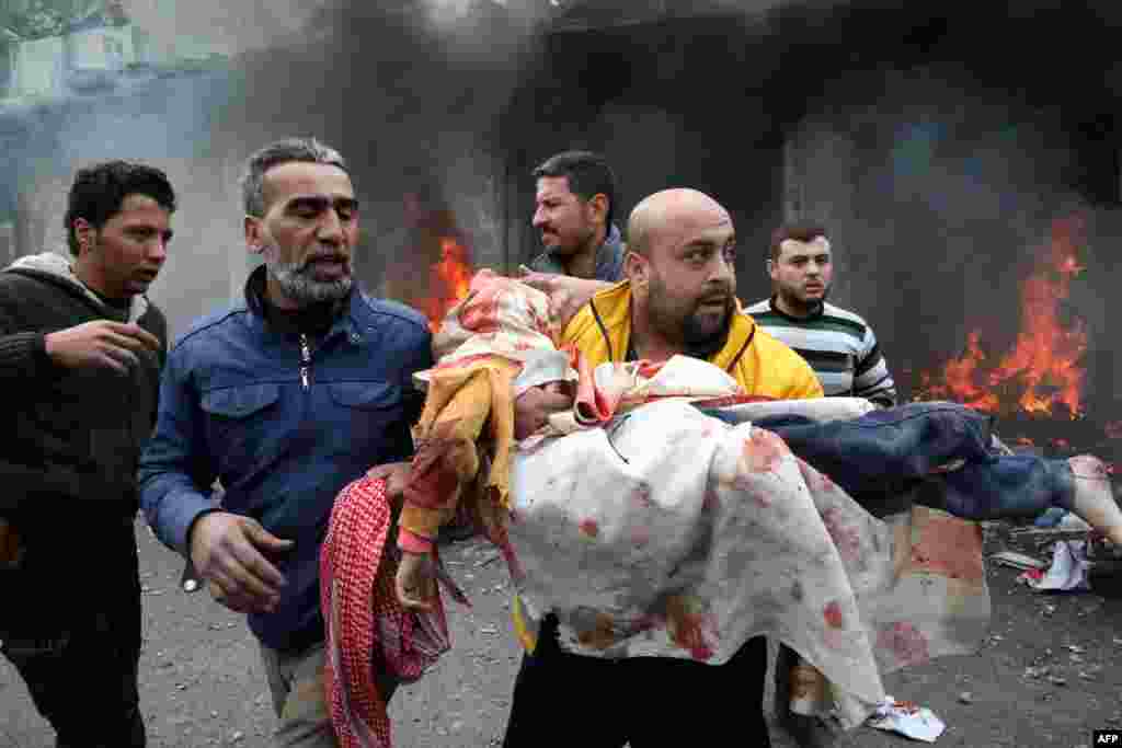Civilians carry a young victim at the scene of an explosion in the town of Azaz in the rebel-controlled northern countryside of Syria&#39;s Aleppo province.