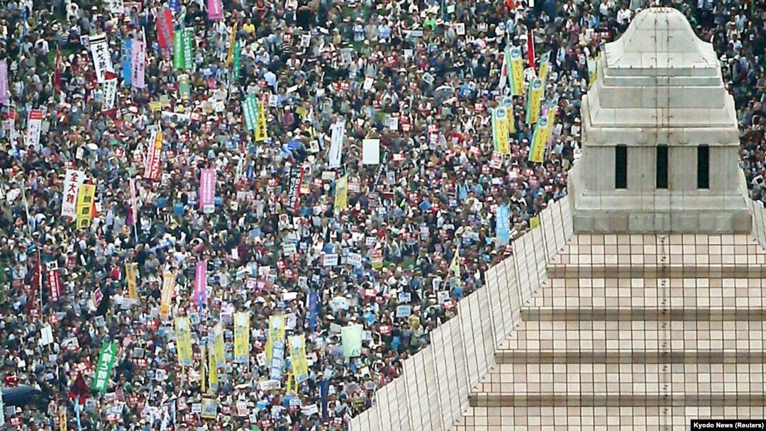 Orang-orang memegang poster dan meneriakkan slogan swat berkumpul untuk memprotes menentang rancangan undang-undang keamanan Perdana Menteri Jepang Shinzo Abe di luar gedung parlemen di Tokyo, 30 Agustus 2015. 