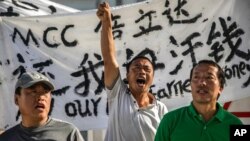 FILE - Chinese laborers Jingbao Zhao, left, Xiaoli Wang, center, and Yongbo Sun protest in front of the Imperial Pacific Casino in Saipan, the Northern Mariana Islands, July 26, 2017. 