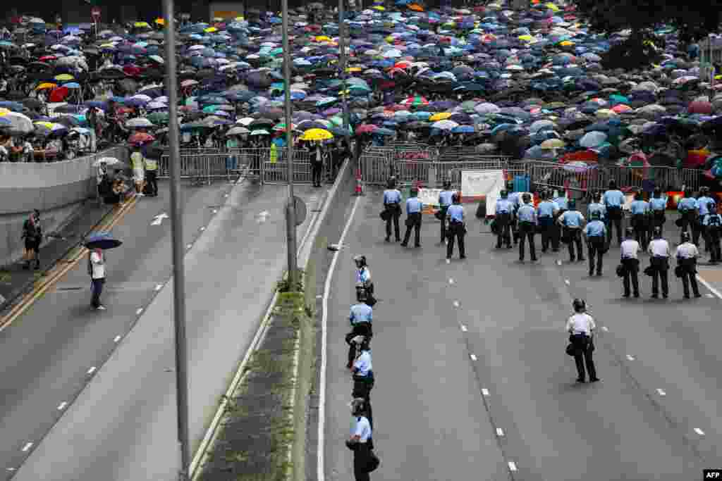 2019年6月12日香港抗议者在港府门外反对香港对中国的引渡法案，警察在道路上巡逻。数以万计的抗议者封锁了主要道路，致使香港中部地区瘫痪。上午稍晚时候，随着人群继续扩大，立法会官员表示，他们将把法案的二读&ldquo;推迟到更晚的日期&rdquo;。