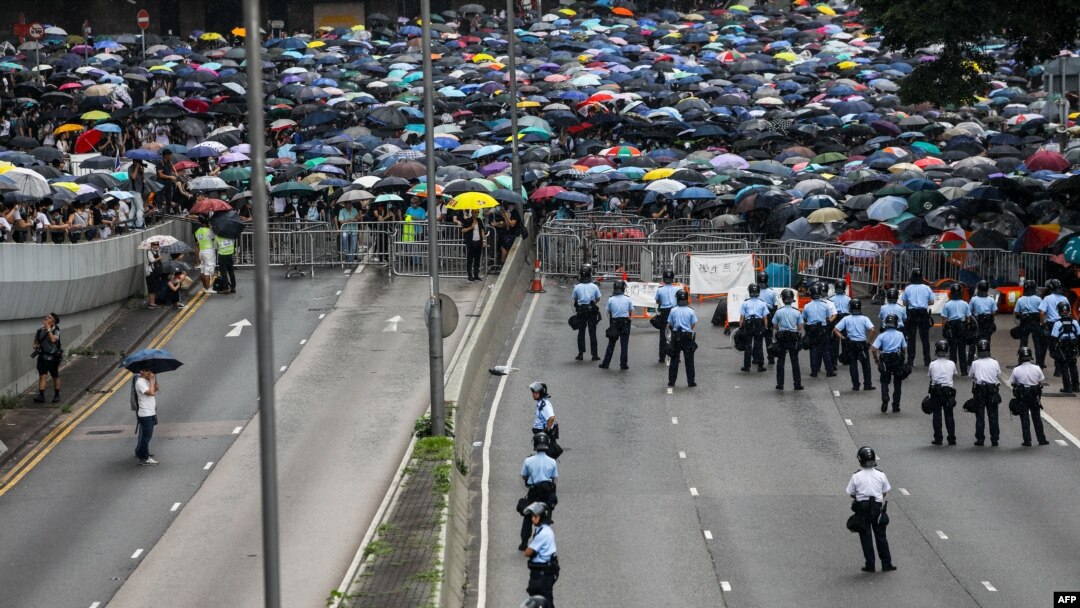 Seorang polisi menjaga jalan saat para pengunjuk rasa menggelar demonstrasi menentang RUU Ekstradisi yang kontroversial di luar kantor pemerintah di Hong Kong, 12 Juni 2019. (Foto: AFP)