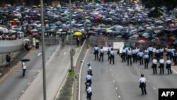 Seorang polisi menjaga jalan saat para pengunjuk rasa menggelar demonstrasi menentang RUU Ekstradisi yang kontroversial di luar kantor pemerintah di Hong Kong, 12 Juni 2019. (Foto: AFP)