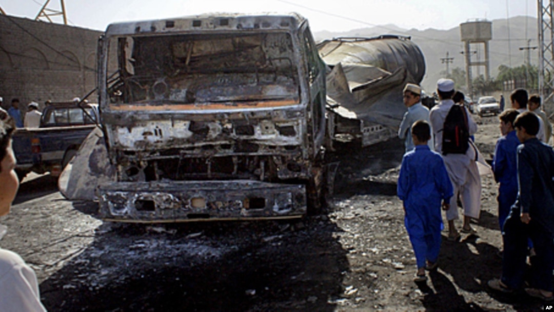 Pakistani youngsters look to a burnt NATO oil tanker caused by alleged militants attacked in Landi Kotal near Afghan border in Pakistan, May 21, 2011