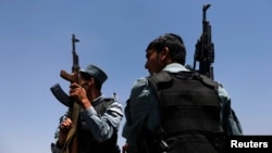 Afghan policemen keep watch as election commission workers move ballot boxes and election material to a polling station in Kabul, June 13, 2014.