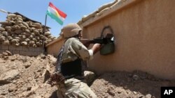 FILE - A Kurdish Peshmerga fighter is seen taking his position in a gun battle with Islamic State militants.