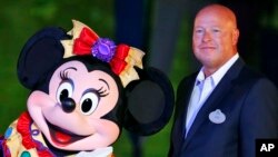 FILE - In this Sept. 11, 2015, file photo, Chairman of Walt Disney Parks and Resorts Bob Chapek poses with Minnie Mouse during a ceremony at the Hong Kong Disneyland, as they celebrate the Hong Kong Disneyland's 10th anniversary. The Walt Disney Co…