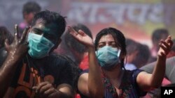 Indians, wearing masks on their faces as preventive measure for swine flu, dance in artificial rain as they celebrate Holi in Ahmadabad, India, March 6, 2015.