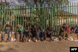 Survivors of the fire that ripped through the five-storey building in the early hours on August 31, 2023 killing 74 people, rest outside of a provisional shelter in Johannesburg on September 1, 2023. (Photo by GUILLEM SARTORIO / AFP)