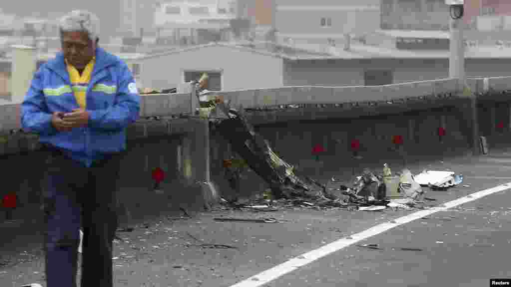 A man walks past next to the wreckage of a TransAsia Airways plane which hit a motorway before crash landing in a river, in New Taipei City.