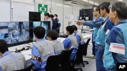 In this photo released by Tokyo Electric Power Company Holdings, executives monitor staff on the ground using a robot to retrieve the first sample of melted fuel debris from inside one of three damaged reactors at the Fukushima Daiichi nuclear power plant, Sept. 10, 2024.