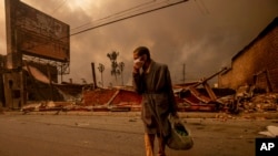 Seorang pria berjalan melewati bangunan yang hancur akibat kebakaran yang melanda wilayah Altadena, California, pada 8 Januari 2025. (Foto: AP/Ethan Swope)