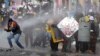 Los manifestantes se protegen de un cañón de agua de la policía durante las protestas contra el gobierno en Bogotá, Colombia, el lunes 28 de junio de 2021.