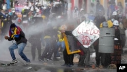 Los manifestantes se protegen de un cañón de agua de la policía durante las protestas contra el gobierno en Bogotá, Colombia, el lunes 28 de junio de 2021.