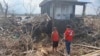 In this photo provided by the Philippine Red Cross, a volunteer talks to a resident beside damaged trees and debris swept by floods caused by Typhoon Usagi in Gonzaga, Cagayan province, northern Philippines on Nov. 15, 2024. 