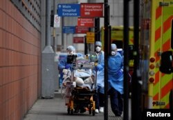 Medical workers move a patient between ambulances outside the Royal London Hospital amid the spread of the coronavirus disease pandemic, London, Jan. 27, 2021.