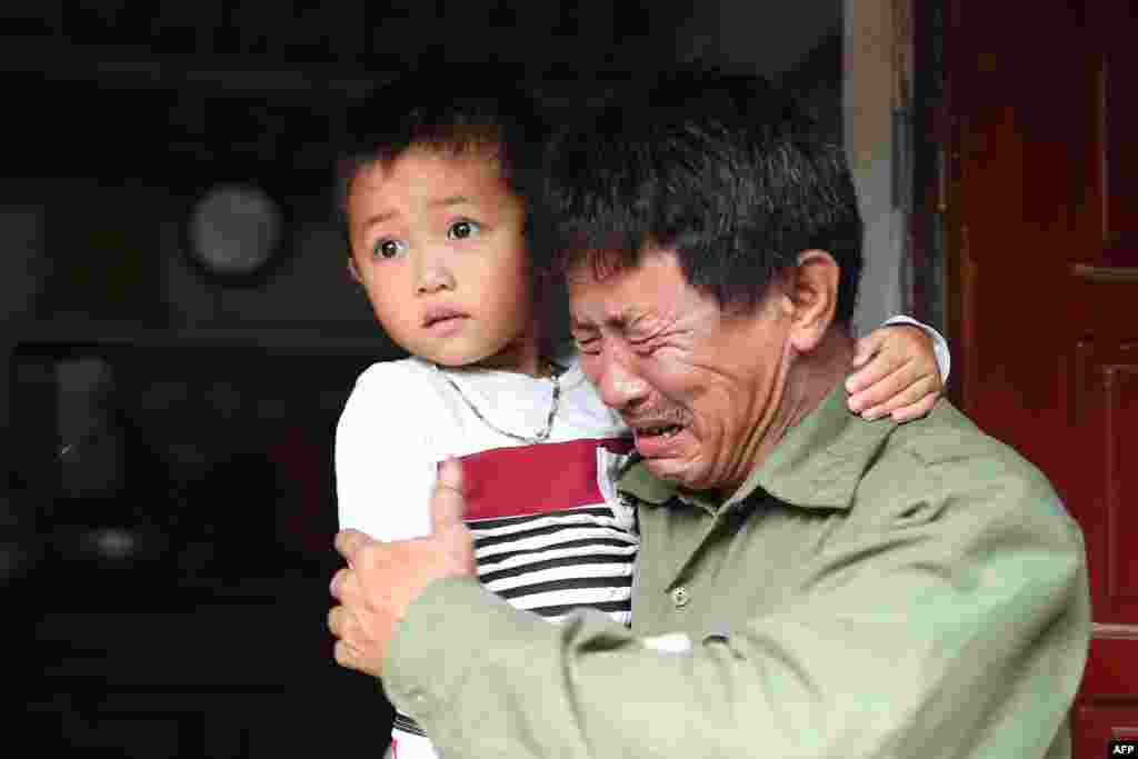Le Minh Tuan, father of 30-year old Le Van Ha, who is feared to be among the 39 people found dead in a truck in Britain, cries while holding Ha&#39;s son outside their house in Vietnam&#39;s Nghe An province.