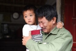 Le Minh Tuan, father of 30-year old Le Van Ha, who is feared to be among the 39 people found dead in a truck in Britain, cries while holding Ha's son outside their house in Vietnam's Nghe An province.