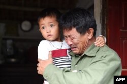 Le Minh Tuan, father of 30-year old Le Van Ha, who is feared to be among the 39 people found dead in a truck in Britain, cries while holding Ha's son outside their house in Vietnam's Nghe An province.