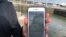 FILE - A National Health Service employee holds up a smartphone displaying a NHS app to trace contacts with people potentially infected with the coronavirus, on the Isle of Wight, Britain, May 5, 2020. 