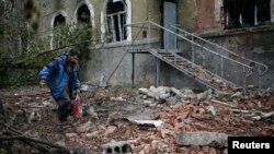 A local resident walks past buildings damaged by recent shelling in the eastern Ukrainian village of Semenovka, July 9, 2014.