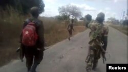 Uma mulher nua é perseguida por homens vestidos com farda militar, junto à vila de Diaca, em Cabo Delgado, Moçambique 