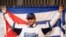 Cuba's baseball player Yulieski Gourriel poses for photographs with the Cuban national flag during a news conference as he joins Japan's Yokohama DeNA BayStars in Yokohama, south of Tokyo, June 2, 2014. 